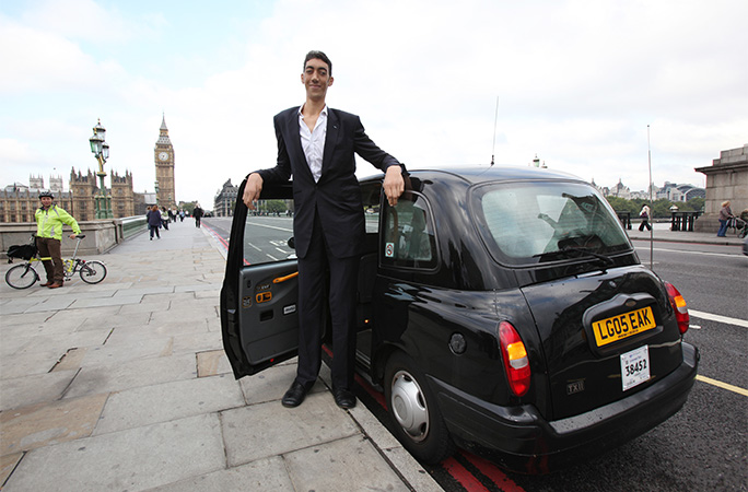 Sultan standing by a black cab
