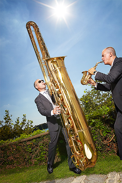 largest saxophone being played next to a regular-sized one