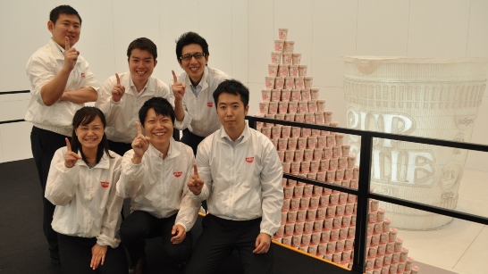 people pointing to ceiling next to largest product pyramid