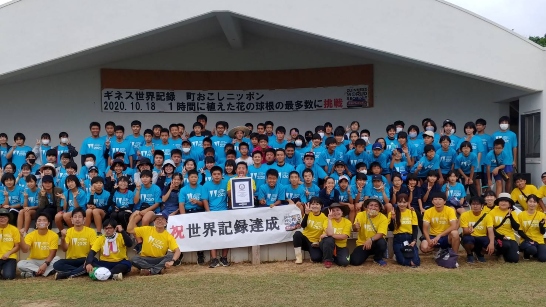 people in blue tshirts and yellow tshirts surrounding a banner and somebody holding a gwr certificate