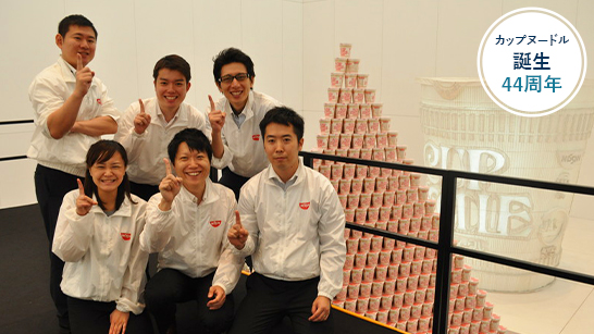 a group of people finger pointing next to largest Largest packaged product pyramid