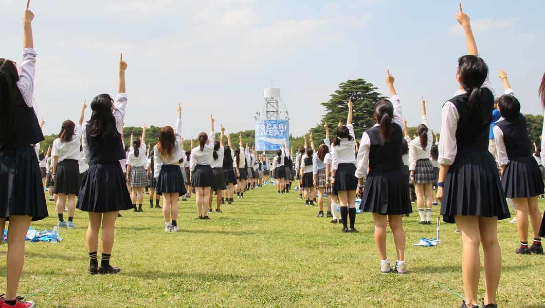 a group of women in skirts pointing at the sky