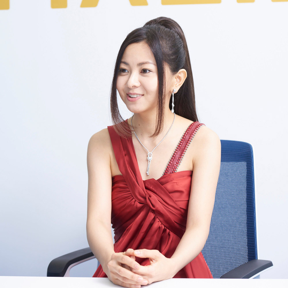 mai sitting on chair wearing red dress