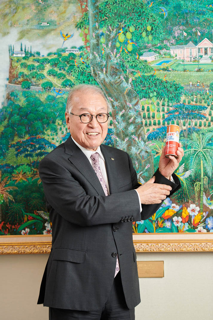 man in suit smiling while holding ucc milk coffee can