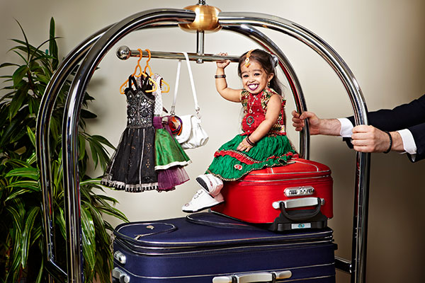 Jyoti amge sitting on small red suitcase